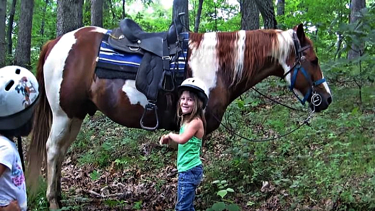 Close-up of girls climbing onto the horse